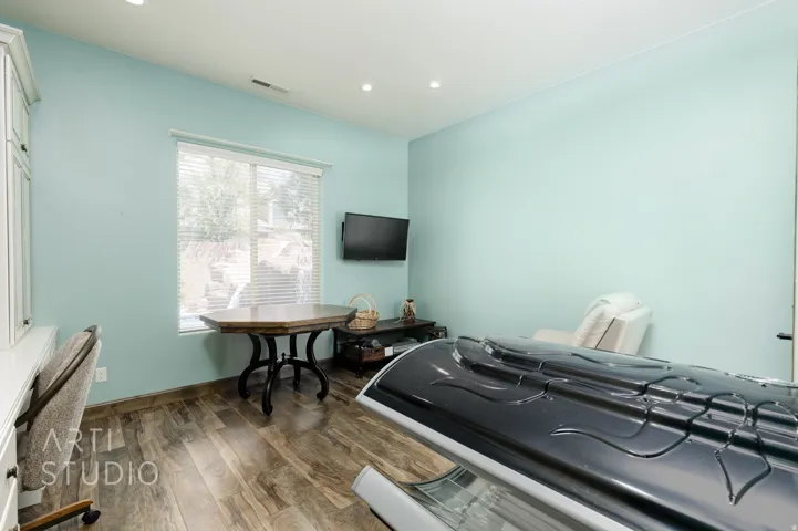 Room with wood-finish flooring, recessed lighting, and a large window with blinds