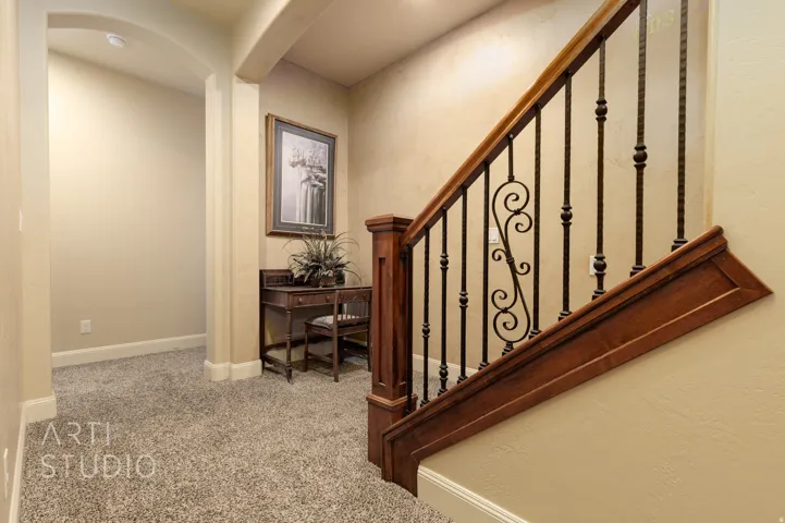 Rich wood staircase with wrought iron balusters featuring decorative scrollwork