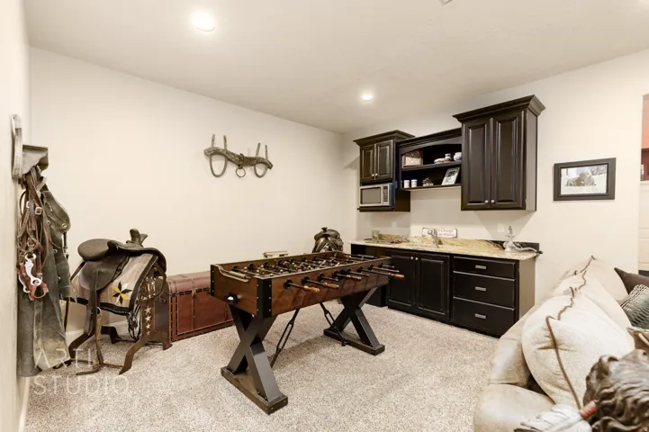 Open room featuring wall-to-wall carpeting, recessed lighting, built-in dark wood cabinetry, a light-toned countertop, and a built-in microwave