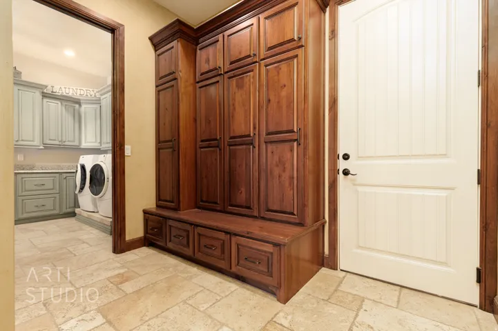 Built-in wood-finish cabinetry with bench seating and storage drawers, complemented by light-toned stone tile flooring