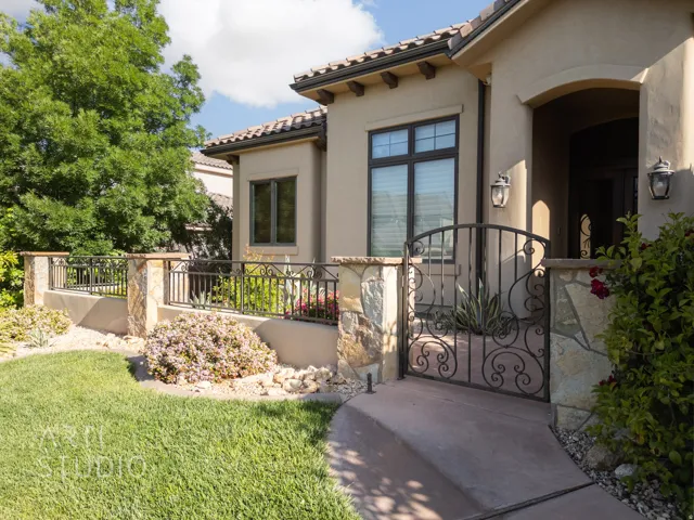 Mediterranean-style exterior featuring a tile roof, stucco finish, and an ornate wrought iron gate