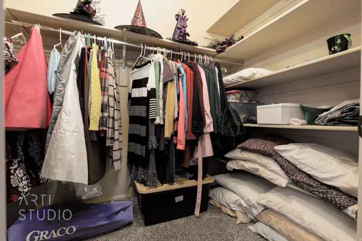 Walk-in closet featuring white built-in shelving, hanging rods, and carpet flooring