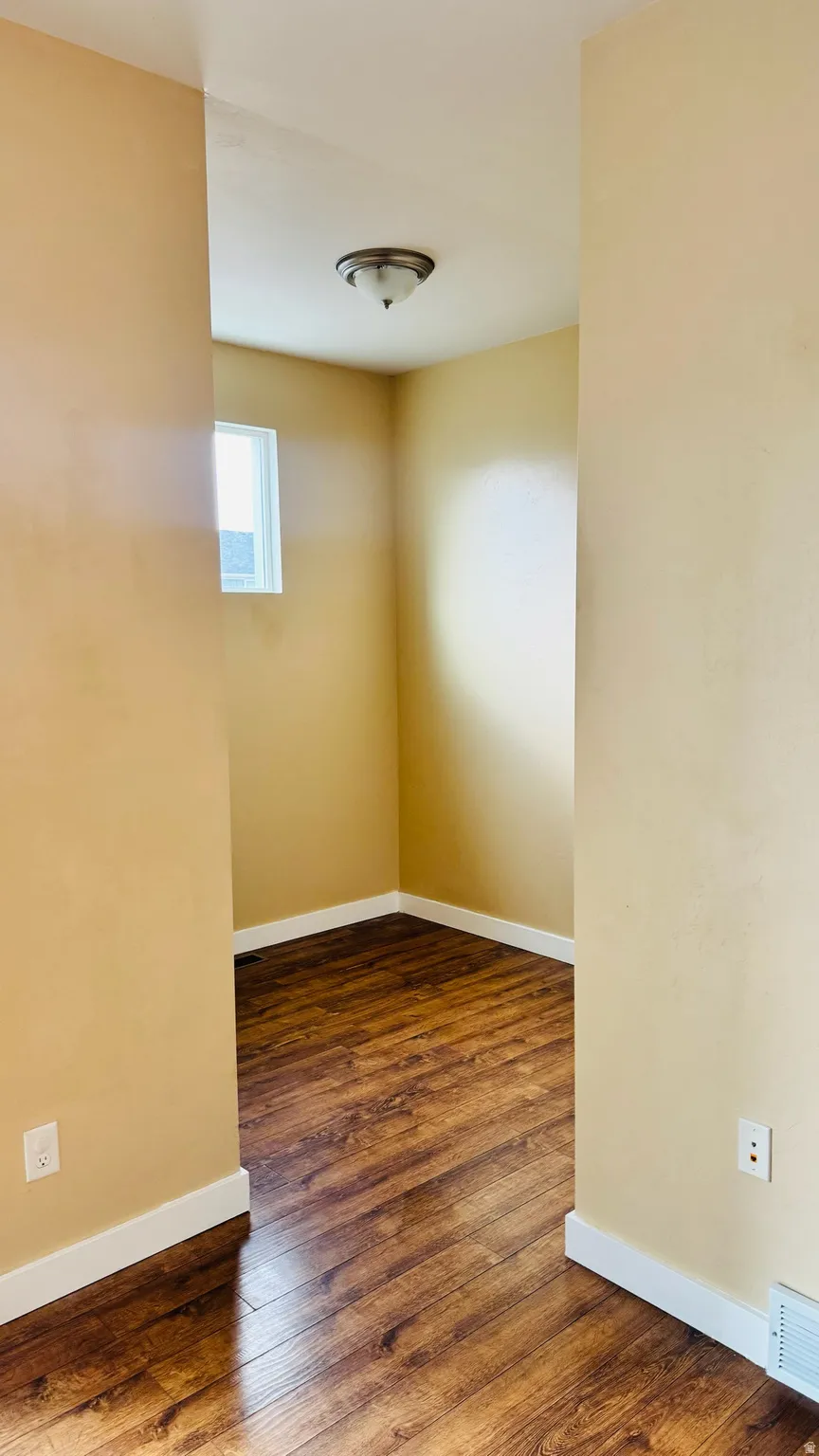 Room with wood-finish flooring, neutral-toned walls, and white baseboards
