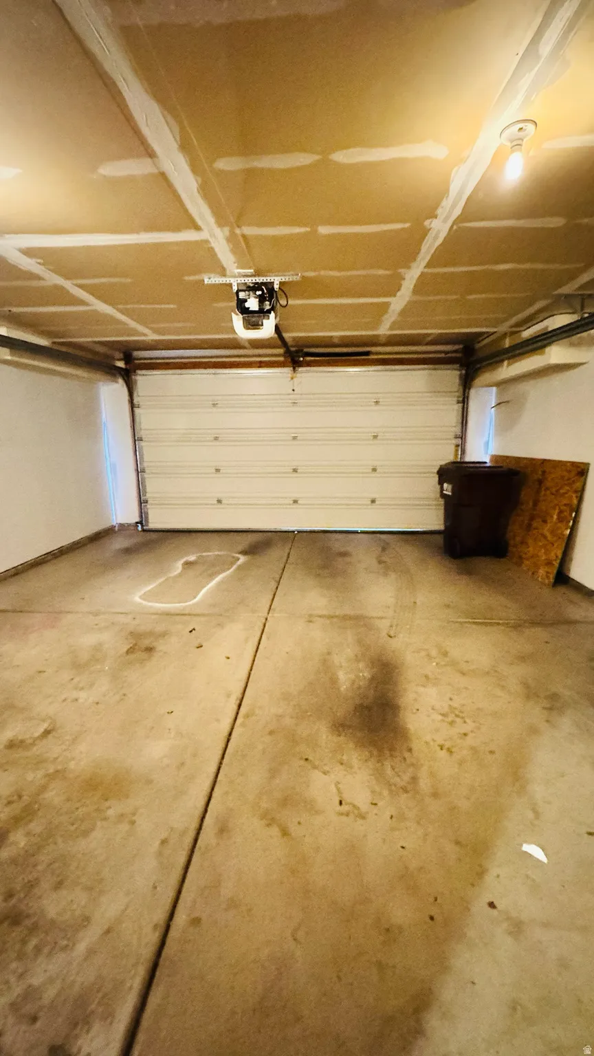 Concrete flooring garage with an automated garage door opener and exposed ceiling joists