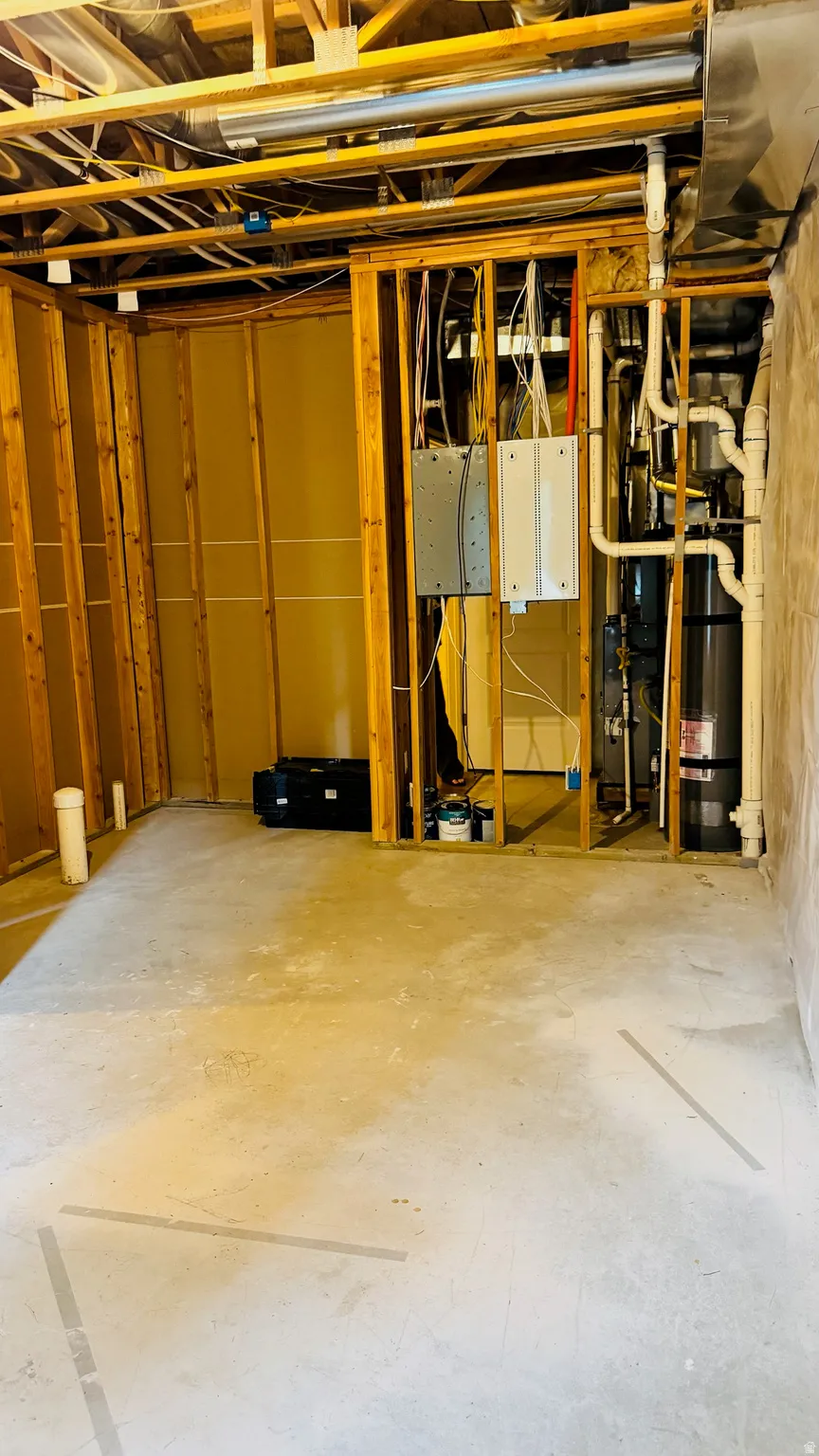 Unfinished basement featuring exposed wood framing, concrete flooring, visible utility piping, and electrical panels