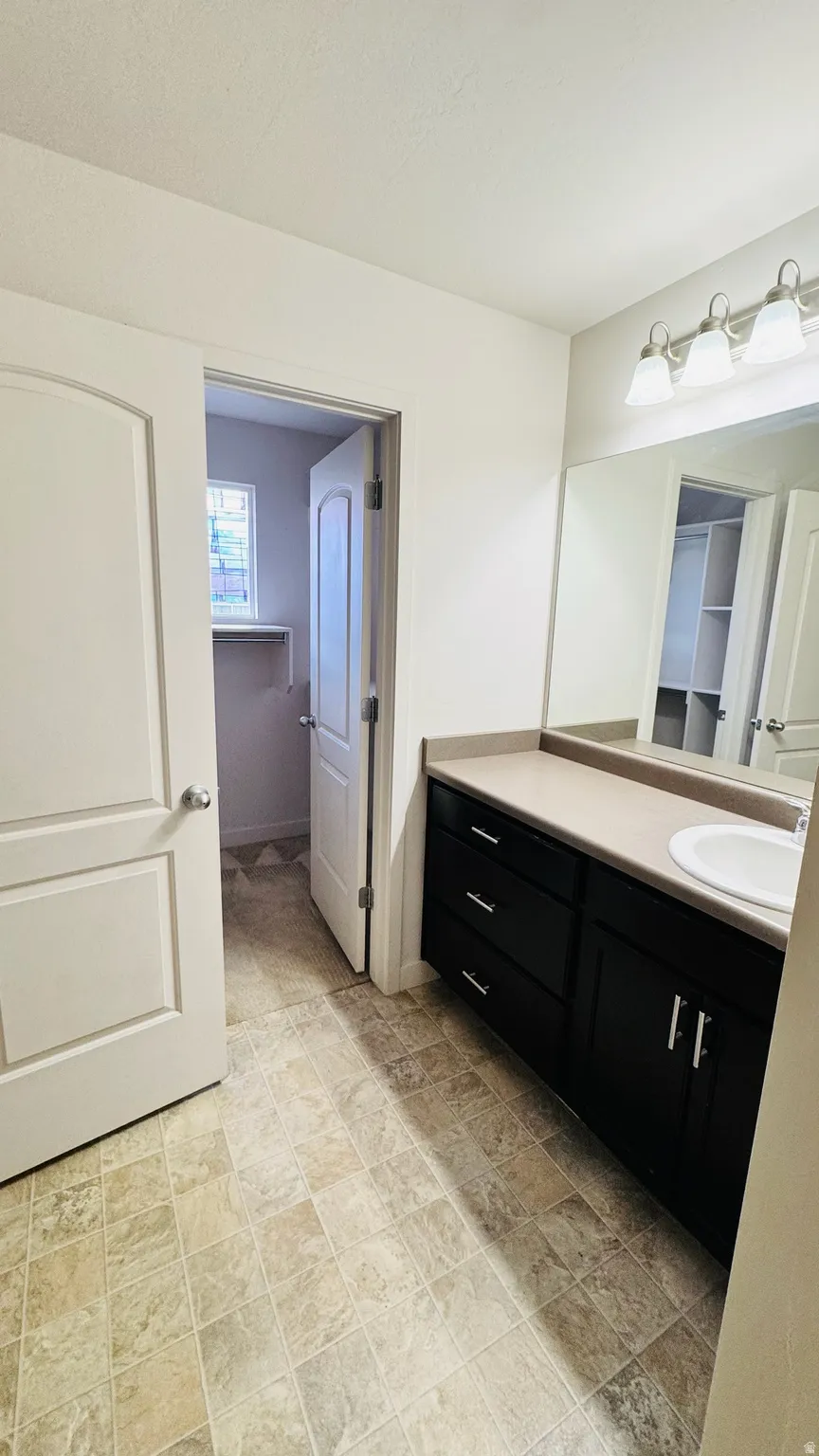 Bathroom featuring a single vanity with a countertop basin and dark wood-finish cabinetry