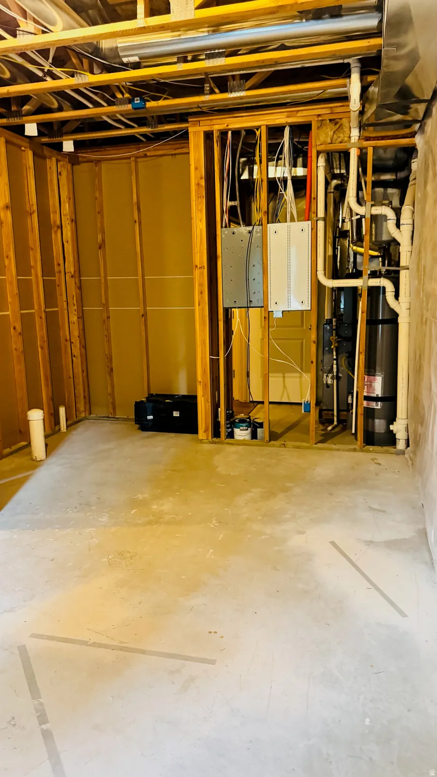 Unfinished basement with concrete flooring, exposed wood framing, and visible utility connections