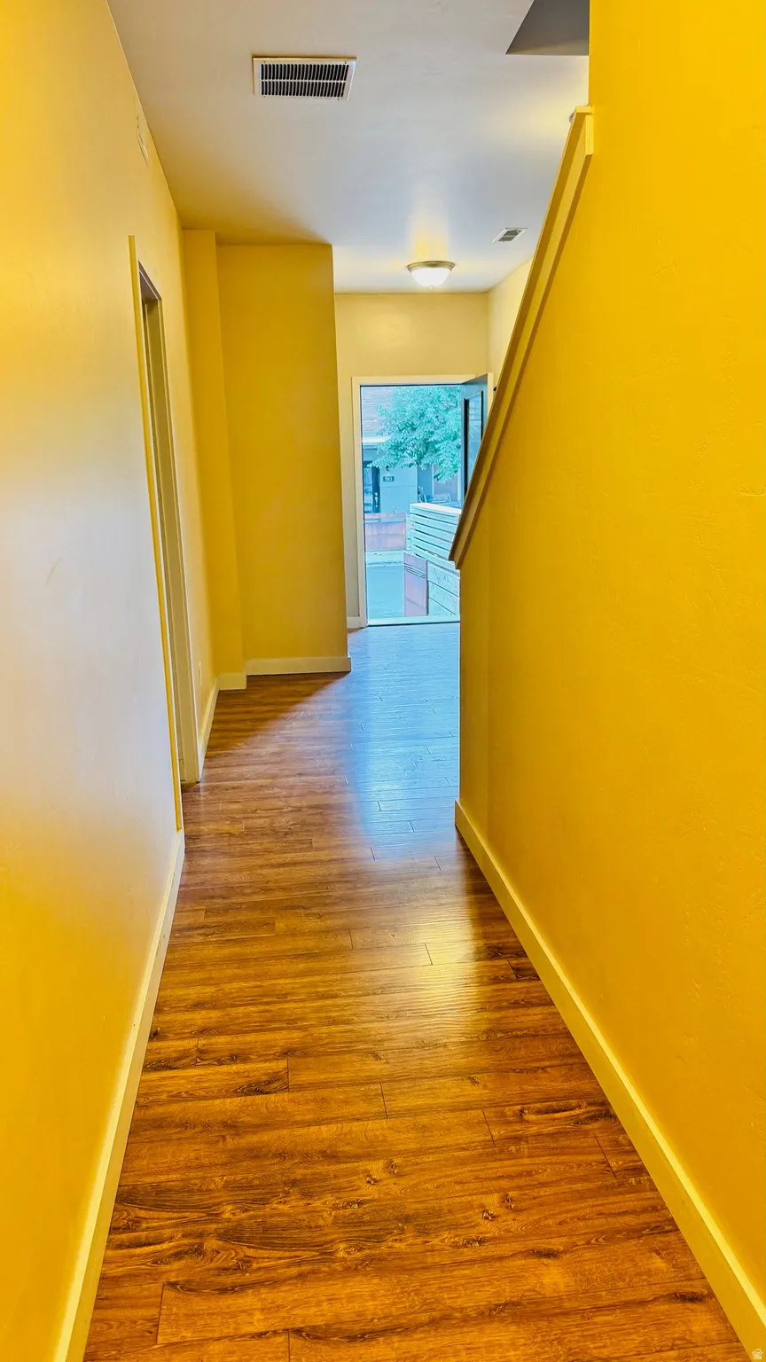 Hallway featuring wood-finish flooring, a flush-mount ceiling light, and a white baseboard trim