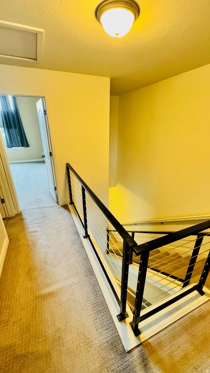 Staircase featuring contemporary cable railing with black posts and a white base