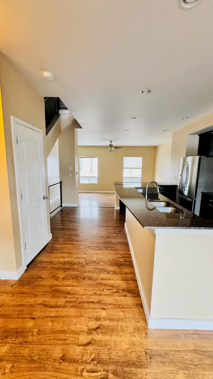Open-concept living area with wood-finish flooring, a kitchen island with stone-finish countertop, and recessed lighting