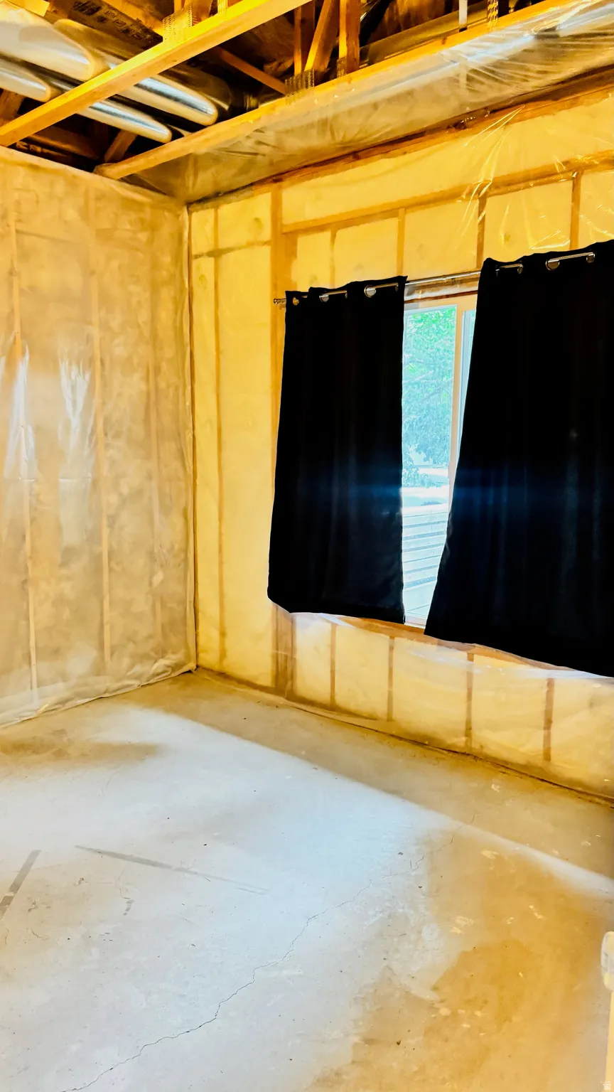 Unfinished lower level with exposed ceiling joists and a single window opening