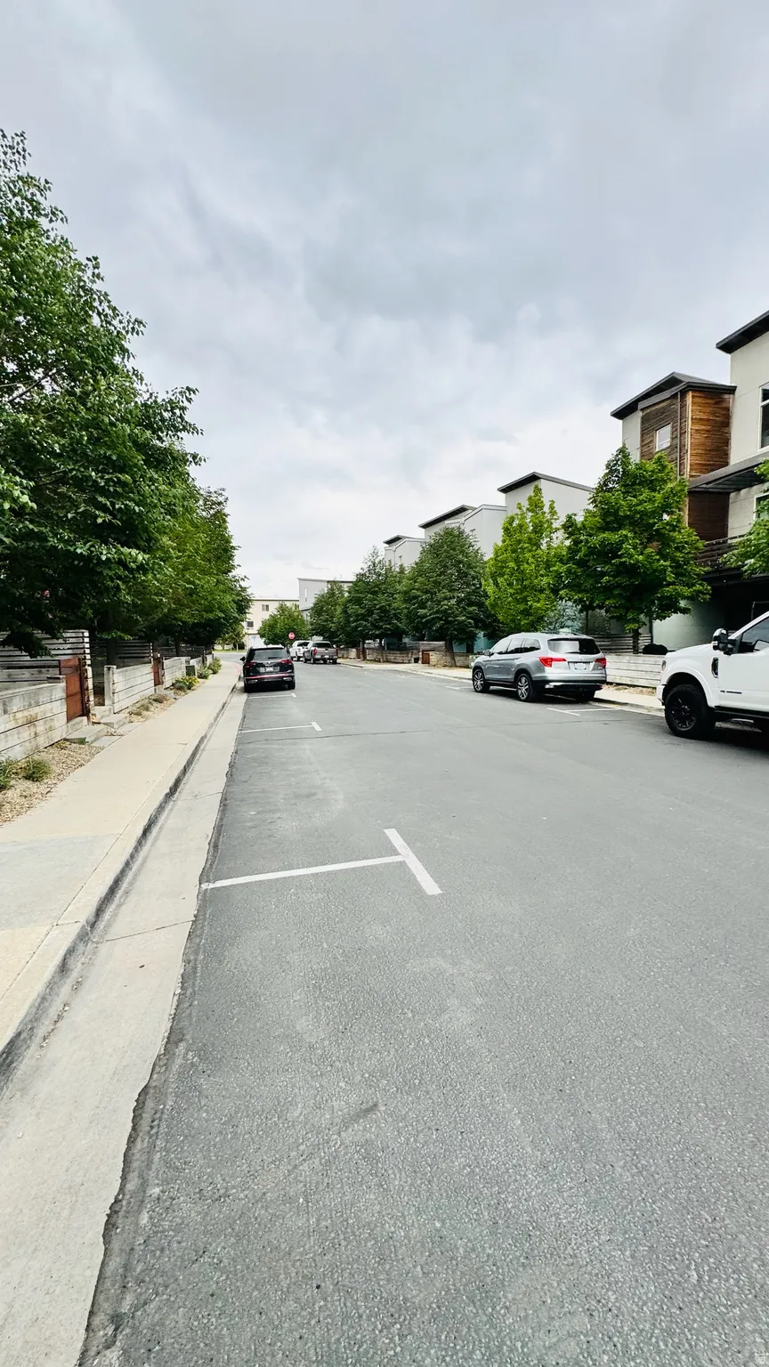Streetscape featuring a paved road with marked parking spaces and concrete sidewalks