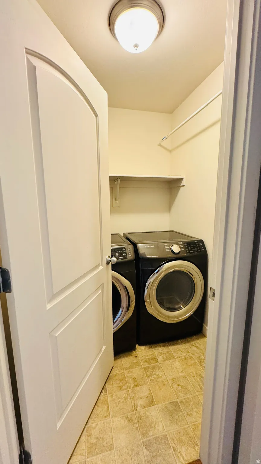 Dedicated laundry closet featuring a built-in shelf, hanging rod, and durable tile flooring