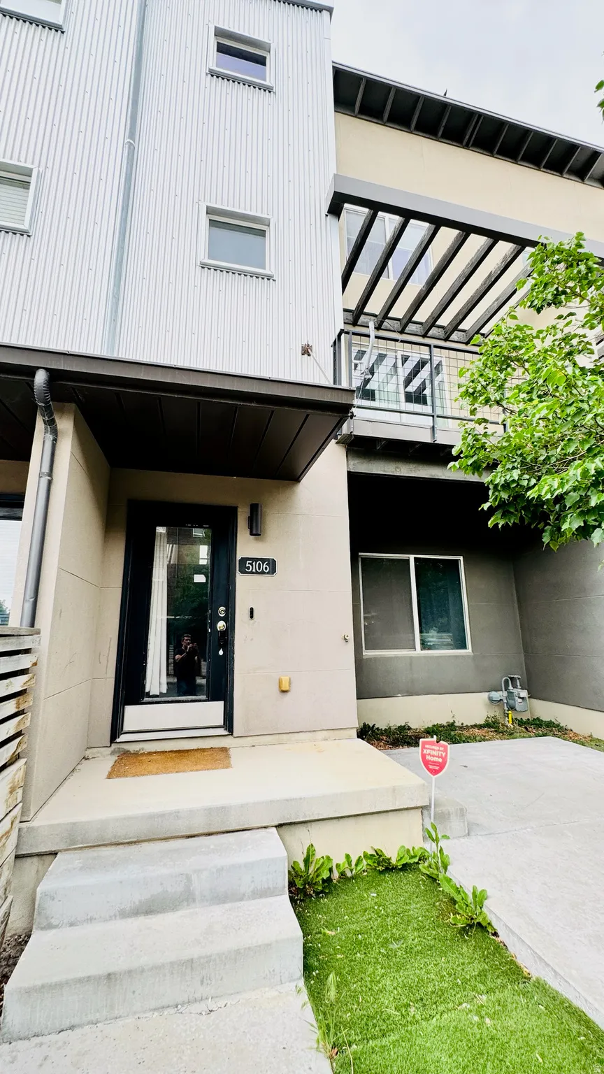 Modern exterior featuring corrugated metal siding, a flat roofline, and a second-story balcony with metal railing and an open pergola