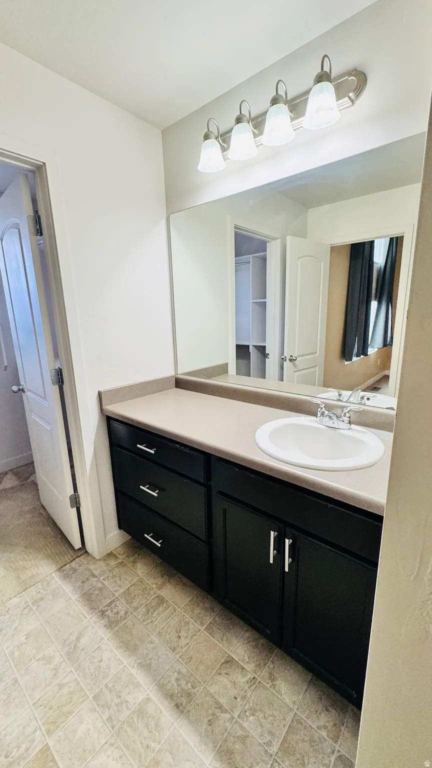 Bathroom vanity featuring a light-toned countertop, undermount sink, and black cabinetry with silver hardware