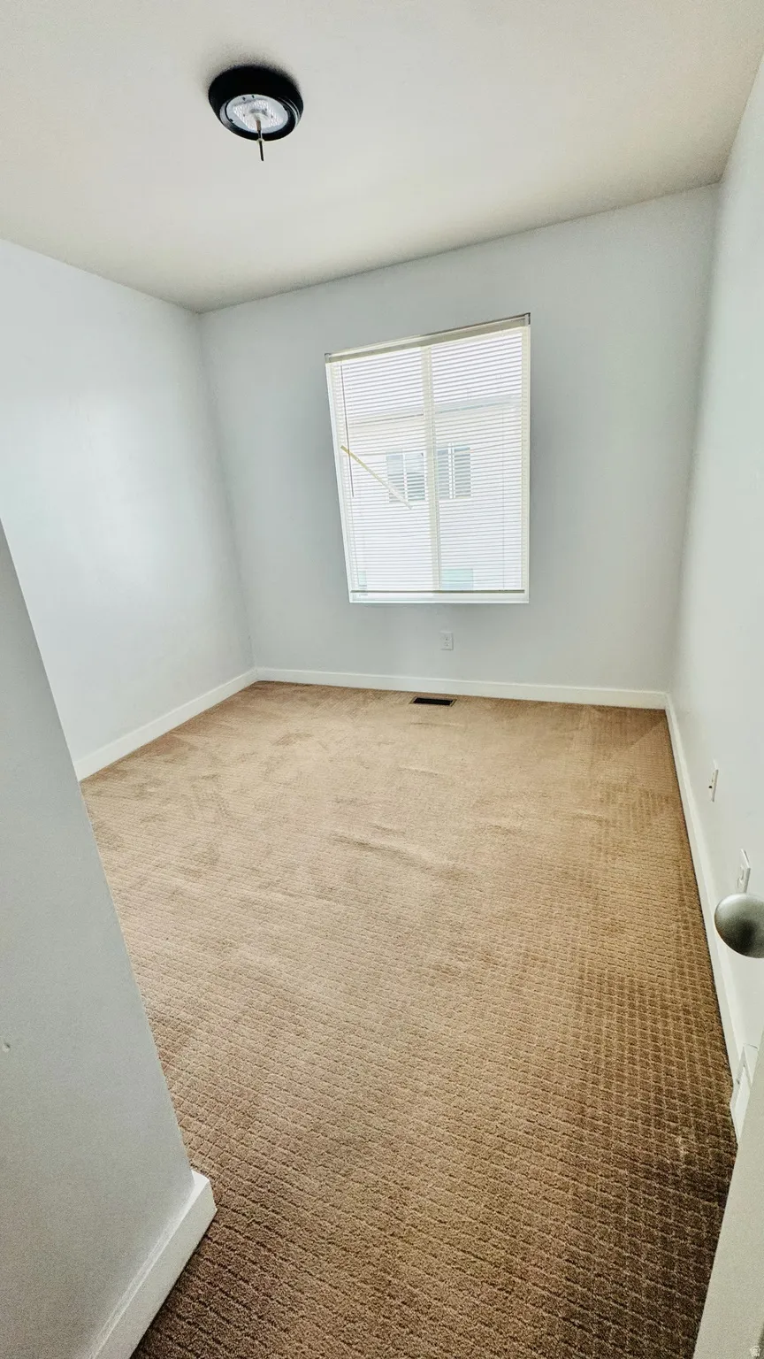 Carpeted room featuring a single window with horizontal blinds, white baseboards, and a flush-mount ceiling light fixture
