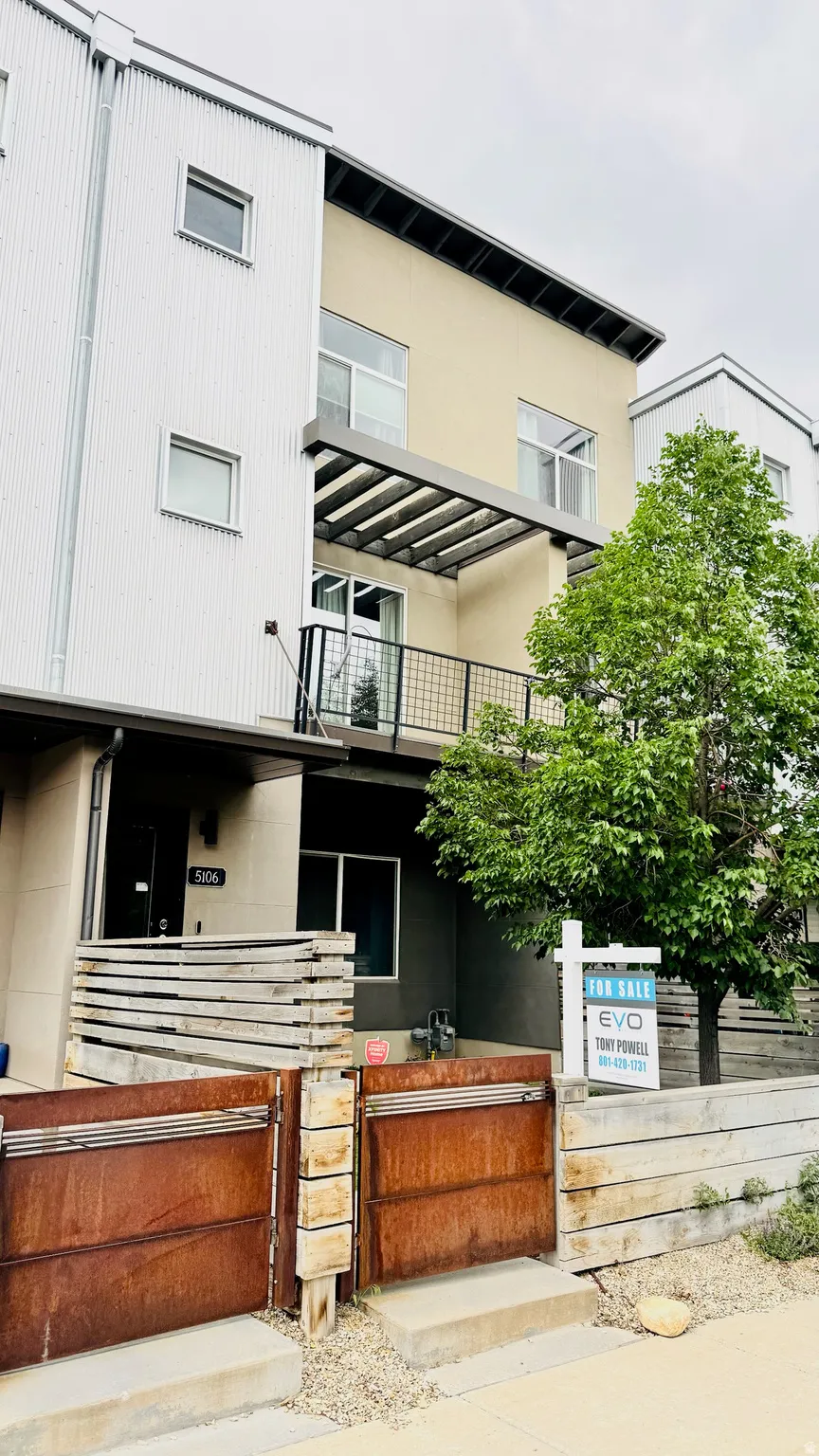 Modern multi-level exterior featuring varied cladding, a balcony with a slatted overhang, and an integrated address plaque