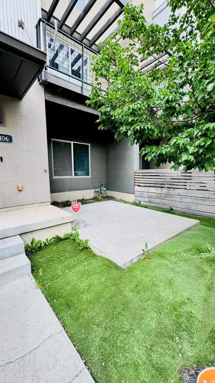 Ground-level patio area featuring concrete paving, artificial turf, and a privacy fence