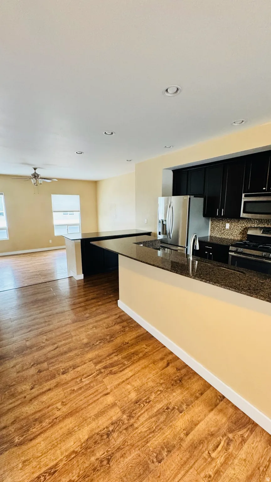 Kitchen featuring dark cabinetry, stainless steel appliances, and a granite-style countertop with a mosaic tile backsplash