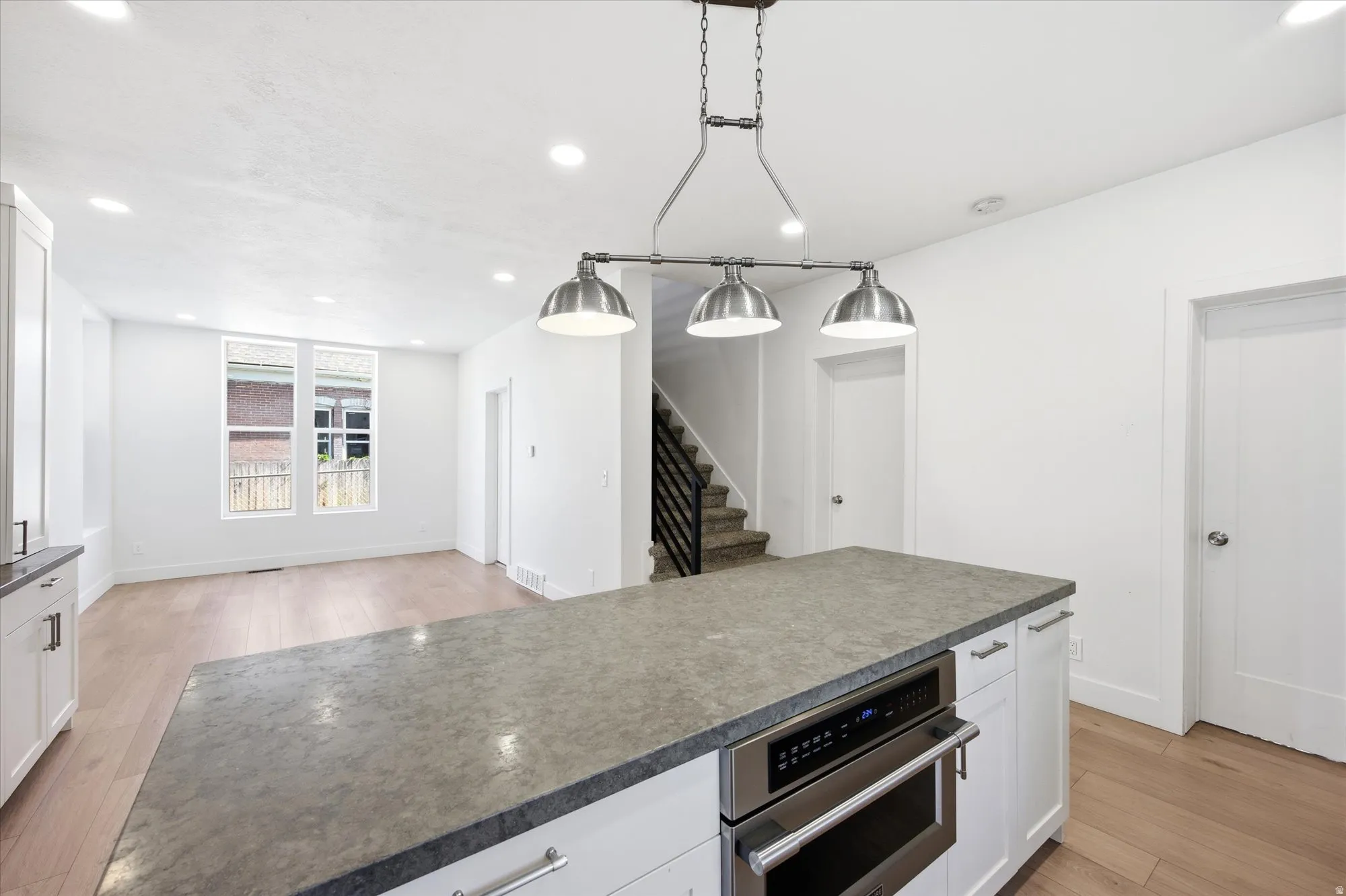 Kitchen island with integrated stainless steel microwave, white cabinetry, and a dark countertop
