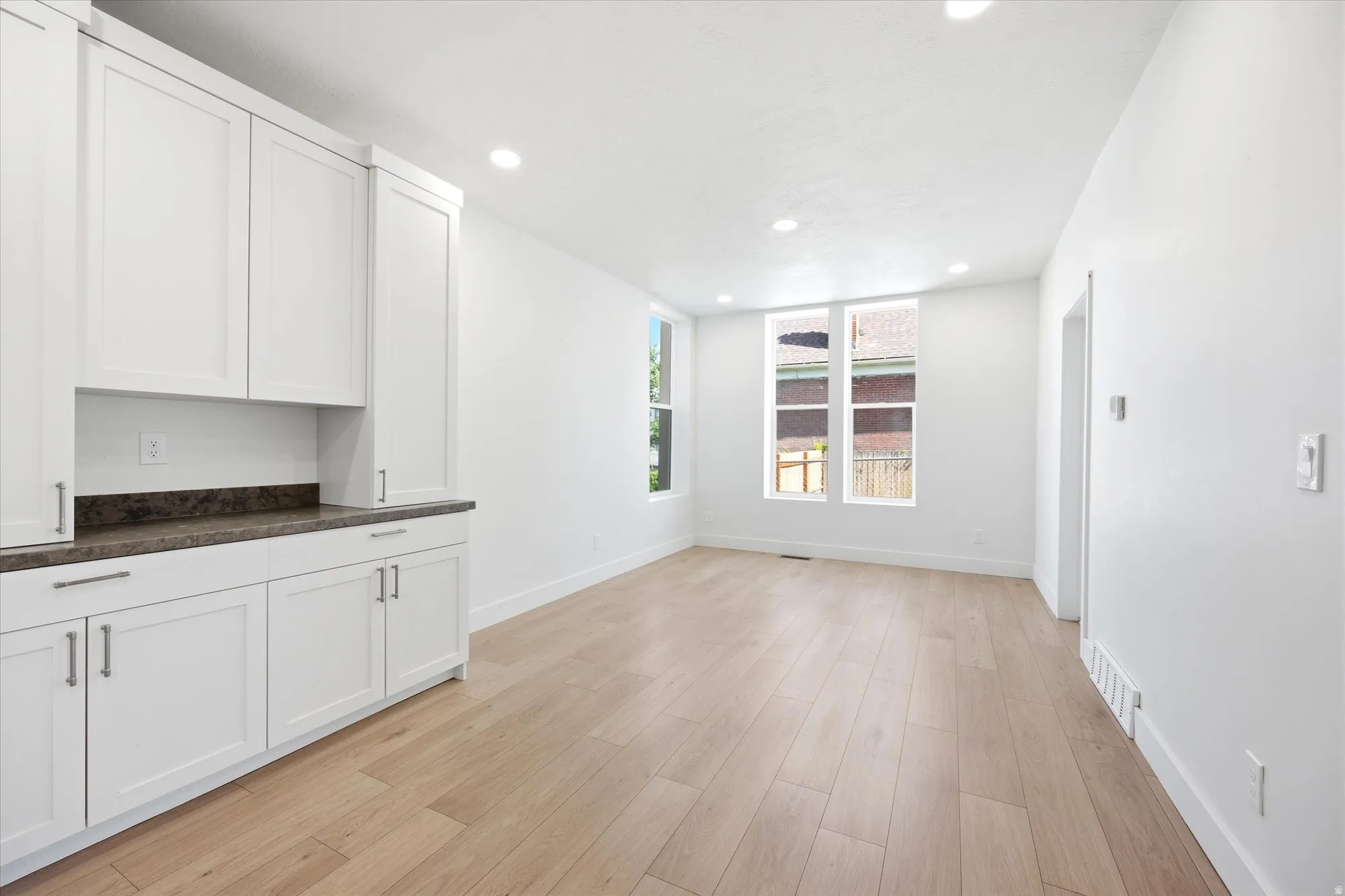 Open concept living space featuring wood-finish flooring, recessed lighting, and bright white walls