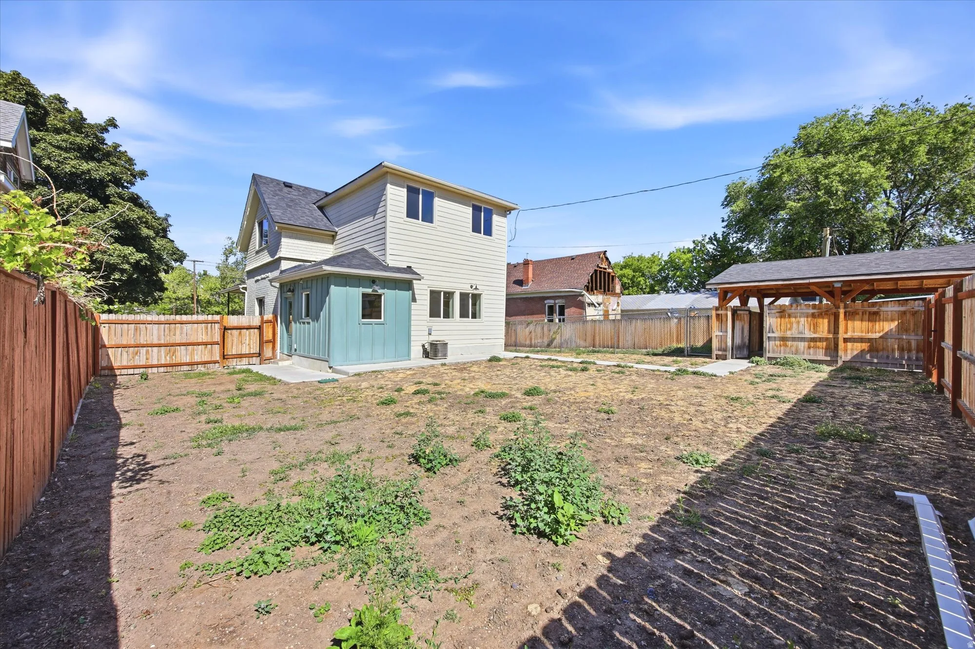 Spacious backyard featuring a newly constructed privacy fence, a covered outdoor structure, and a concrete patio pad