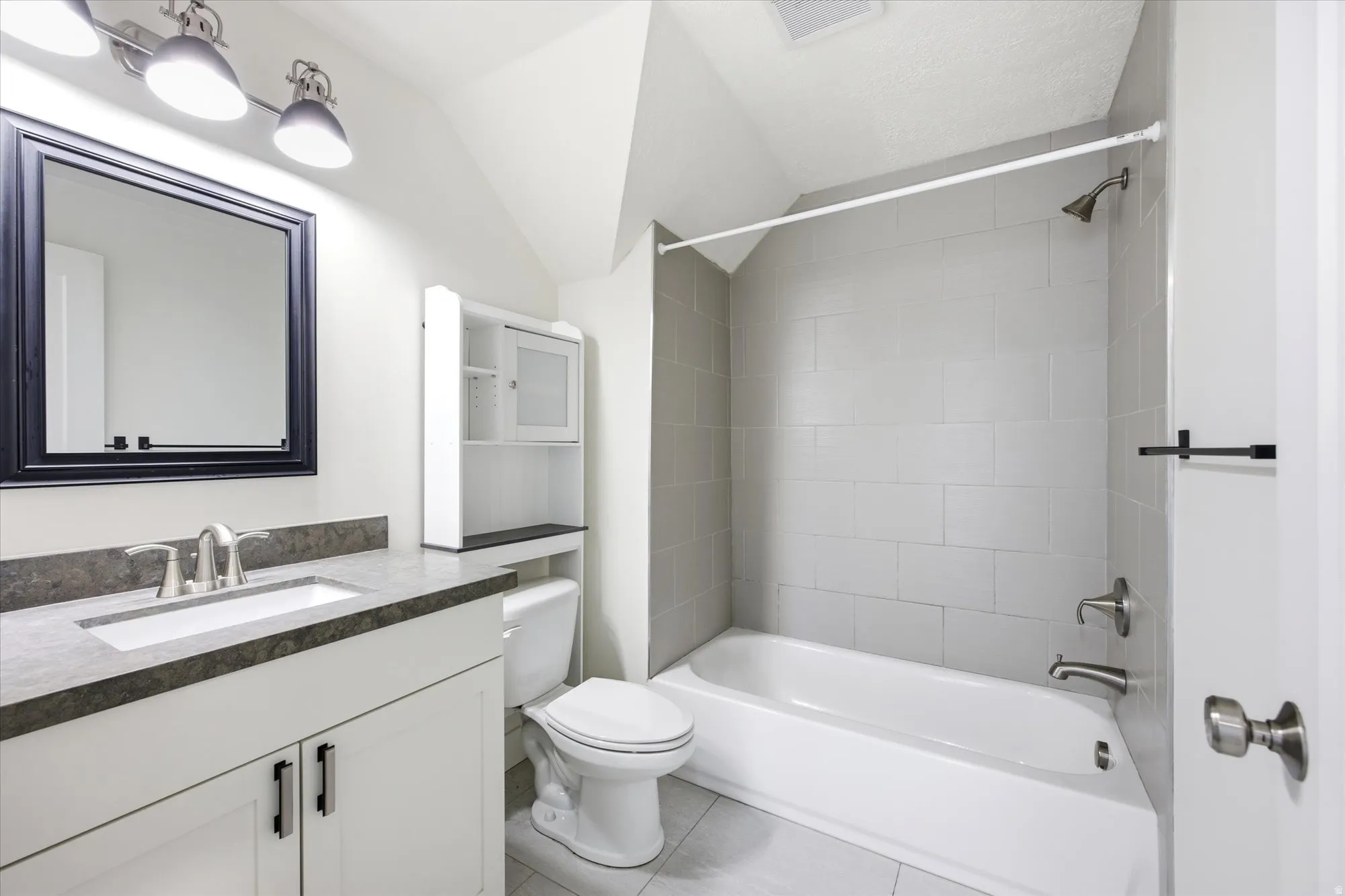 Bathroom featuring a white vanity with dark countertop, rectangular undermount sink, and brushed nickel faucet