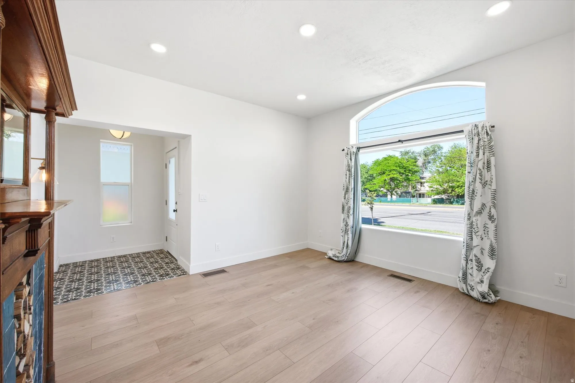 Spacious room featuring light wood-finish flooring, recessed lighting, and an arched picture window