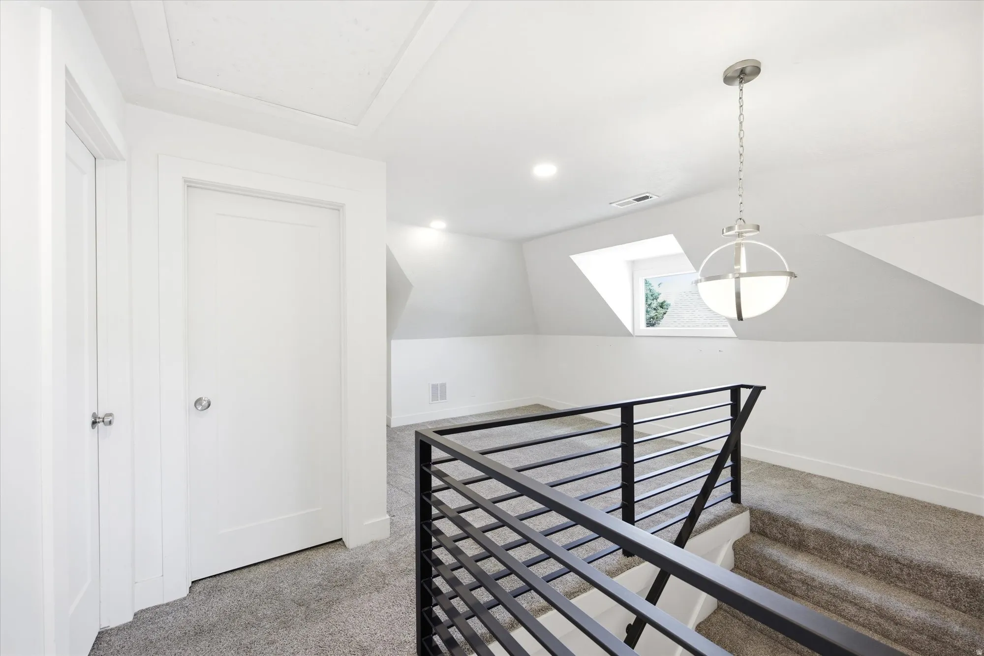 Upper-level landing featuring textured gray carpeting, white walls, and a modern black metal horizontal bar railing
