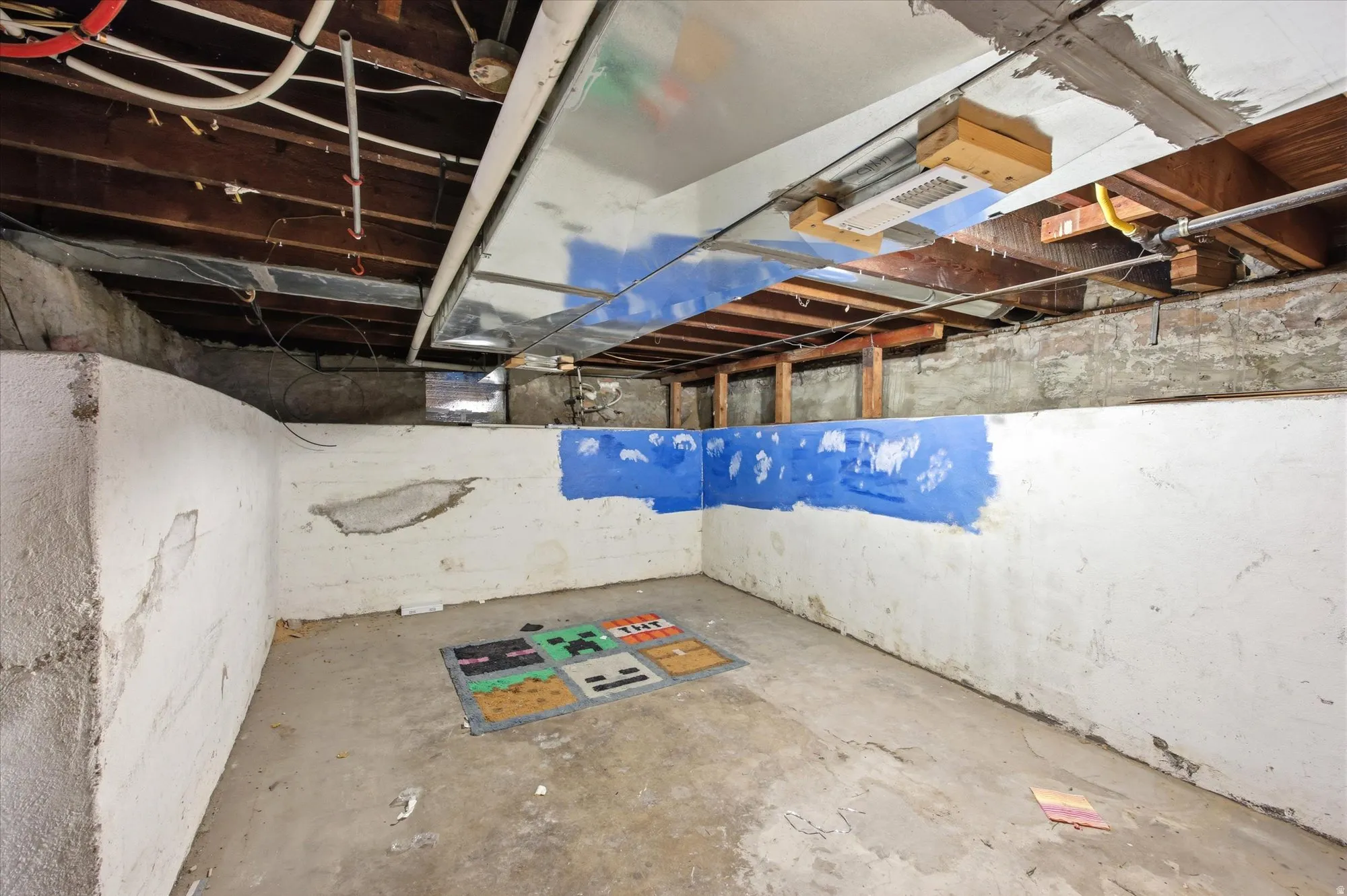 Basement space featuring exposed ceiling joists, visible ductwork, and concrete walls