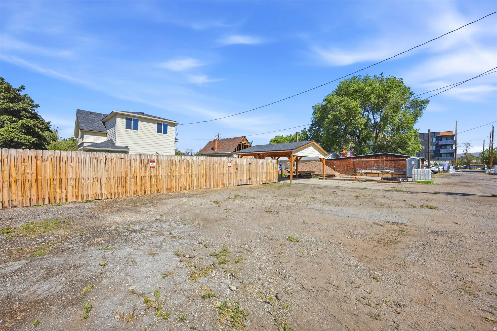 Spacious lot featuring a wood fence perimeter and a partially covered structure