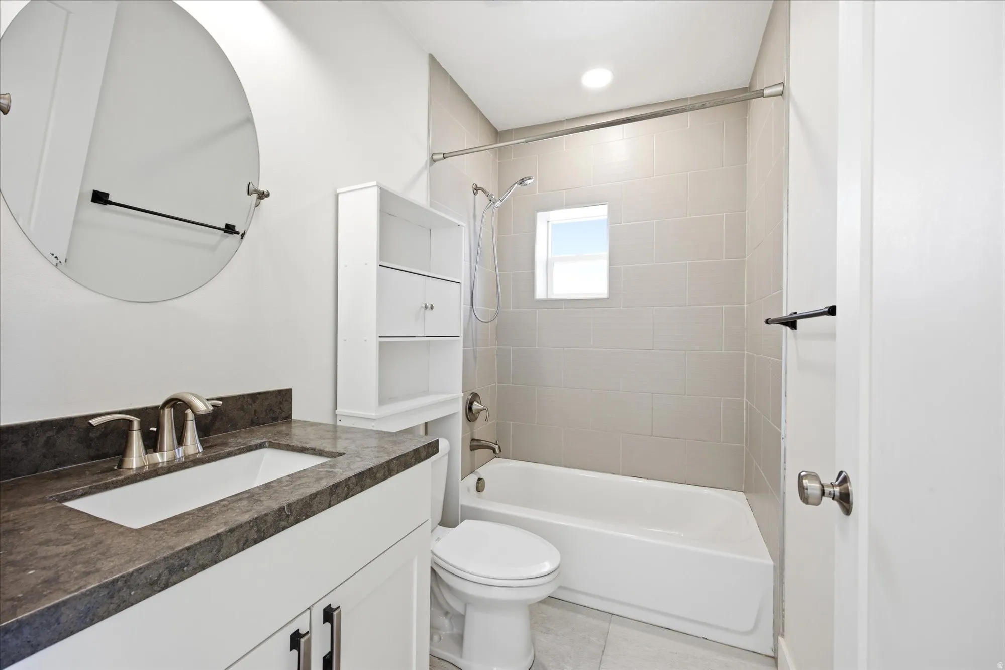 Bathroom featuring a white vanity with an integrated sink, dark countertop, and brushed nickel fixtures
