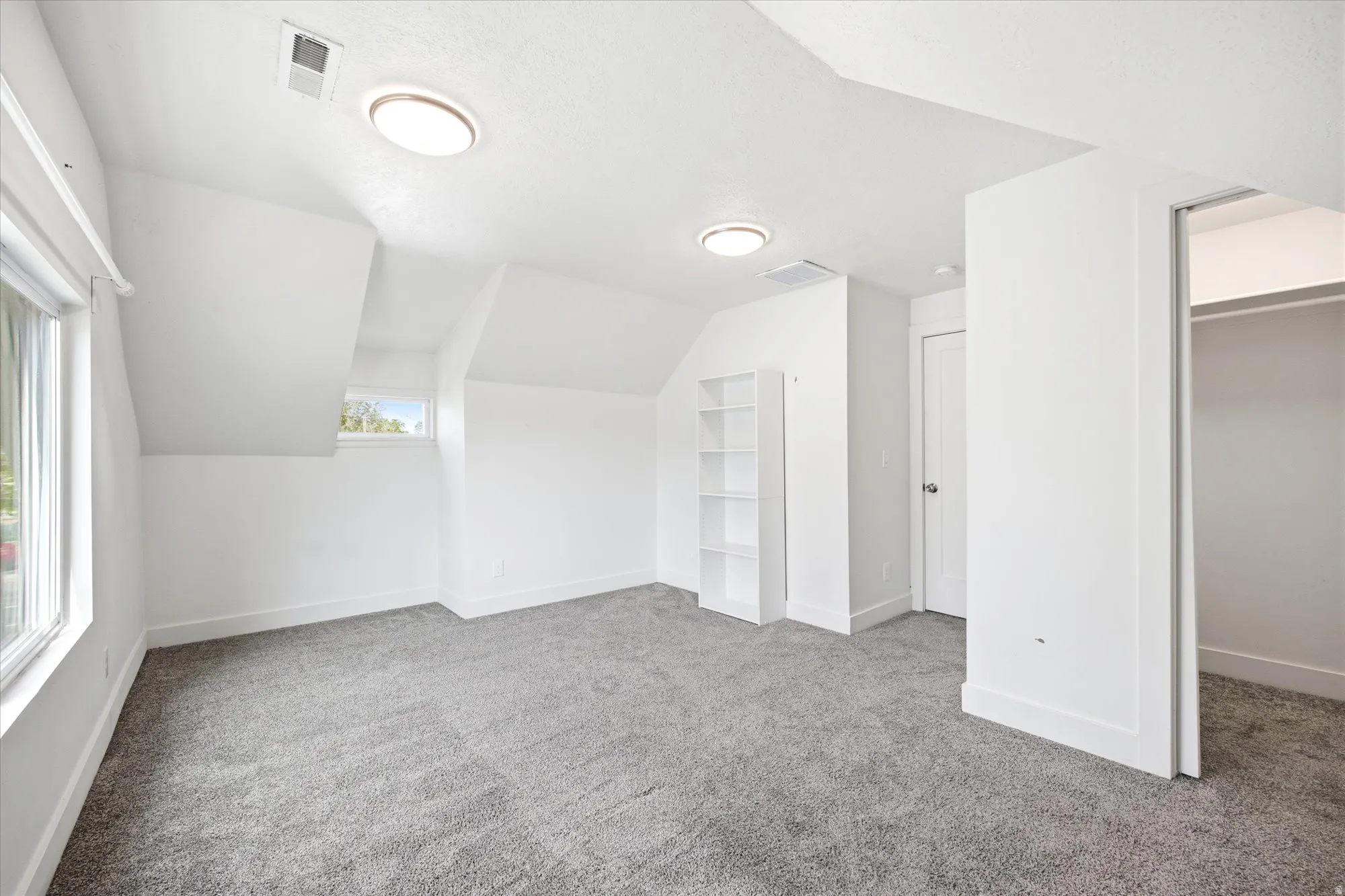Attic room featuring neutral gray carpeting and white painted walls