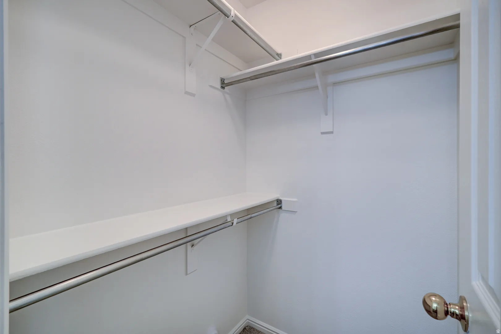 White-painted Primary Bedroom closet featuring multiple shelving units and chrome hanging rods