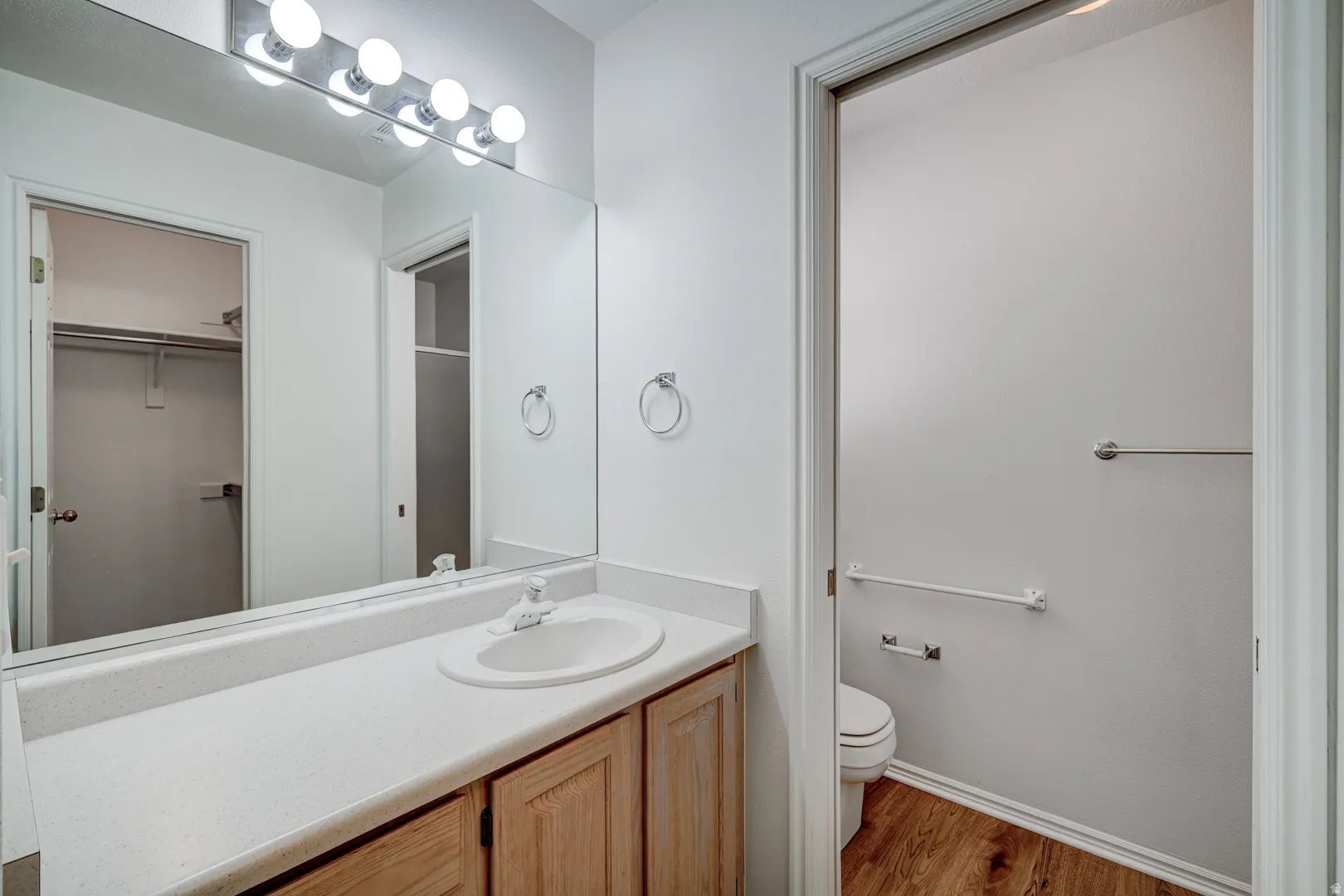 Primary Bathroom vanity with a white countertop and integrated sink, complemented by light wood-finish cabinetry