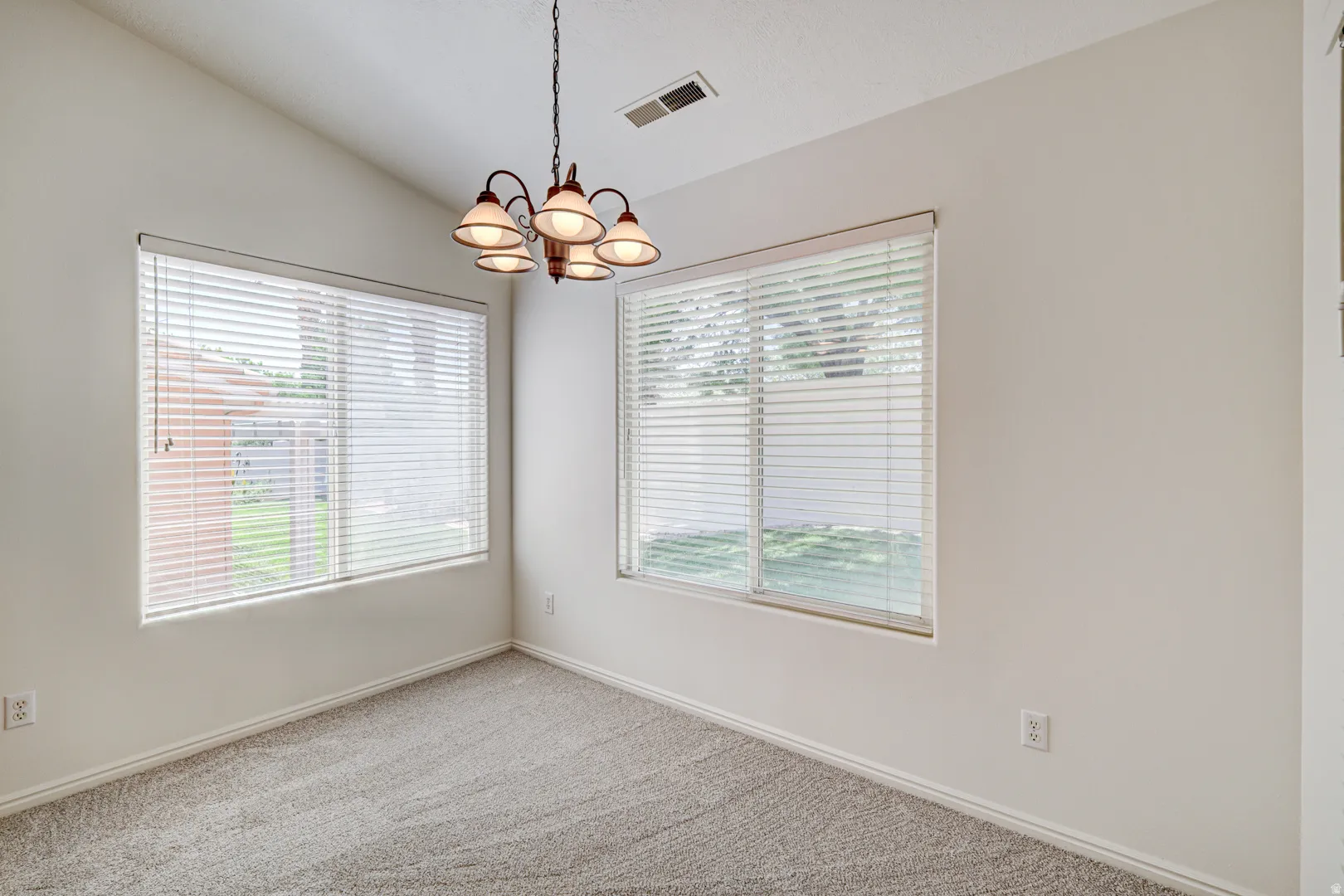 Room featuring a vaulted ceiling and a chandelier with five frosted glass shades