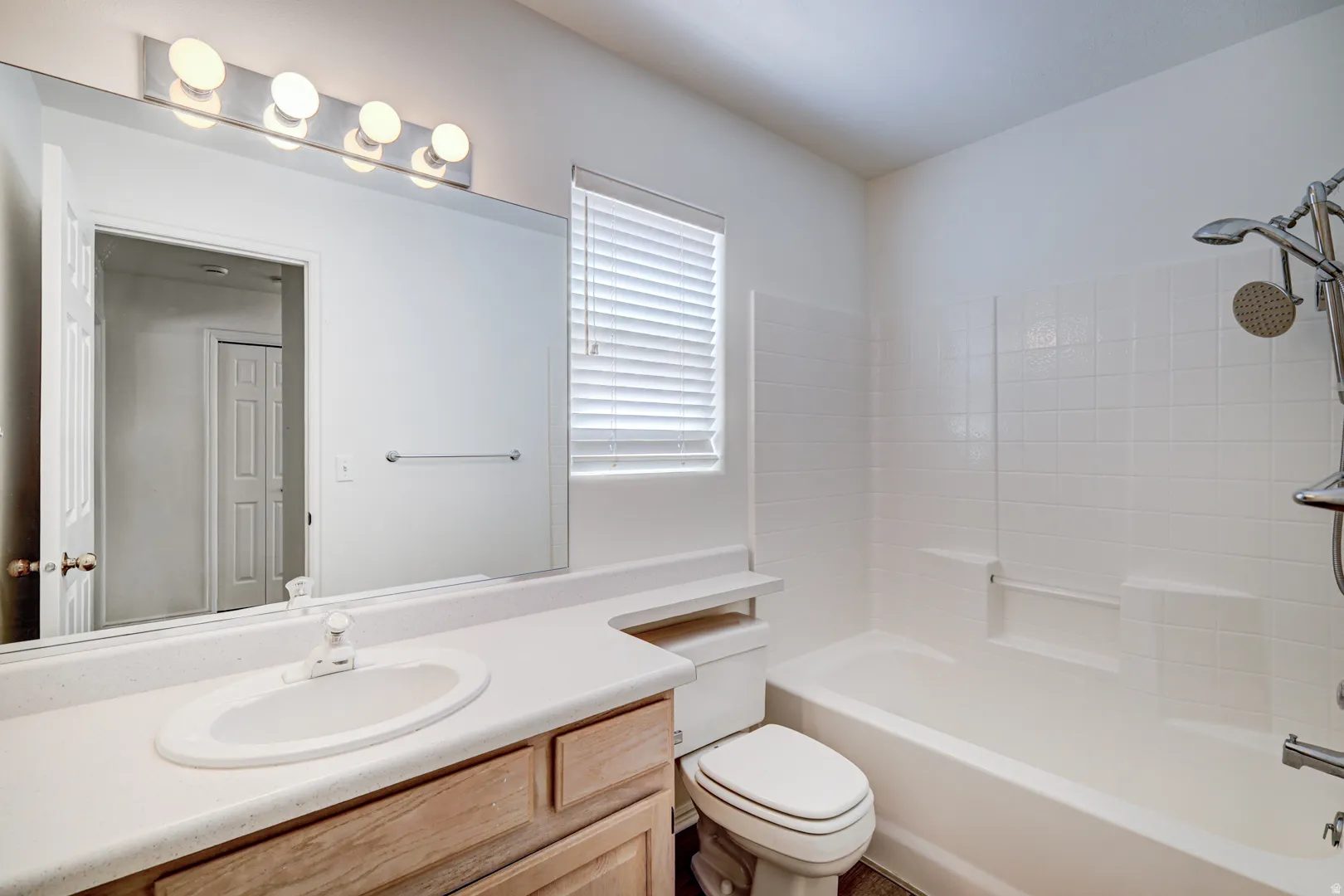 Main Hall Bathroom featuring a single vanity with a white countertop and wood-finish cabinetry, a large mirror, and a five-light fixture