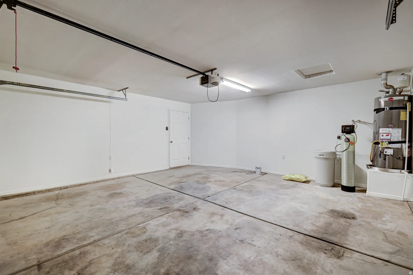 Spacious garage with concrete flooring, fluorescent lighting, and white painted walls
