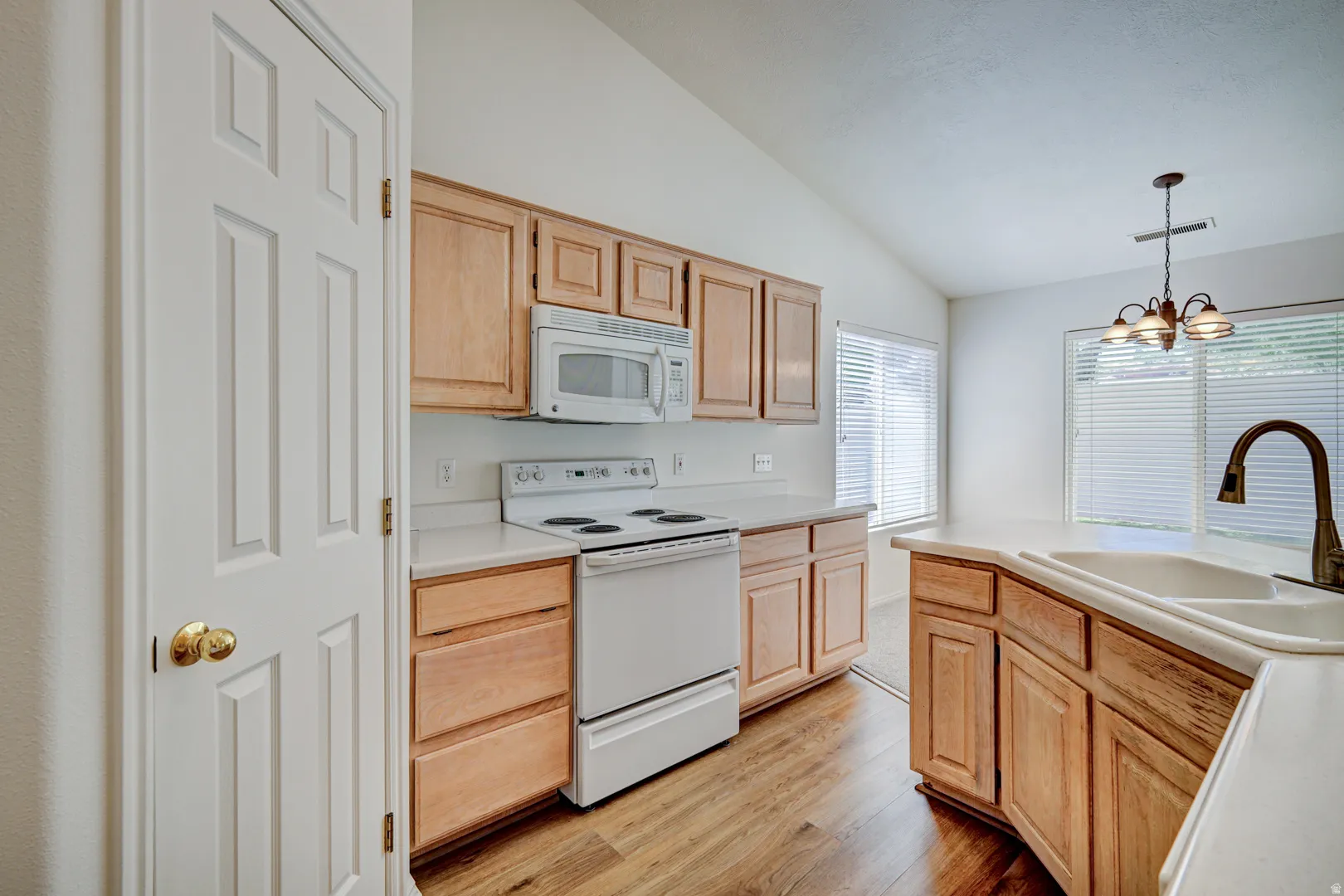 Kitchen featuring wood-finish flooring, light-toned cabinetry, white countertops, and a white appliance suite