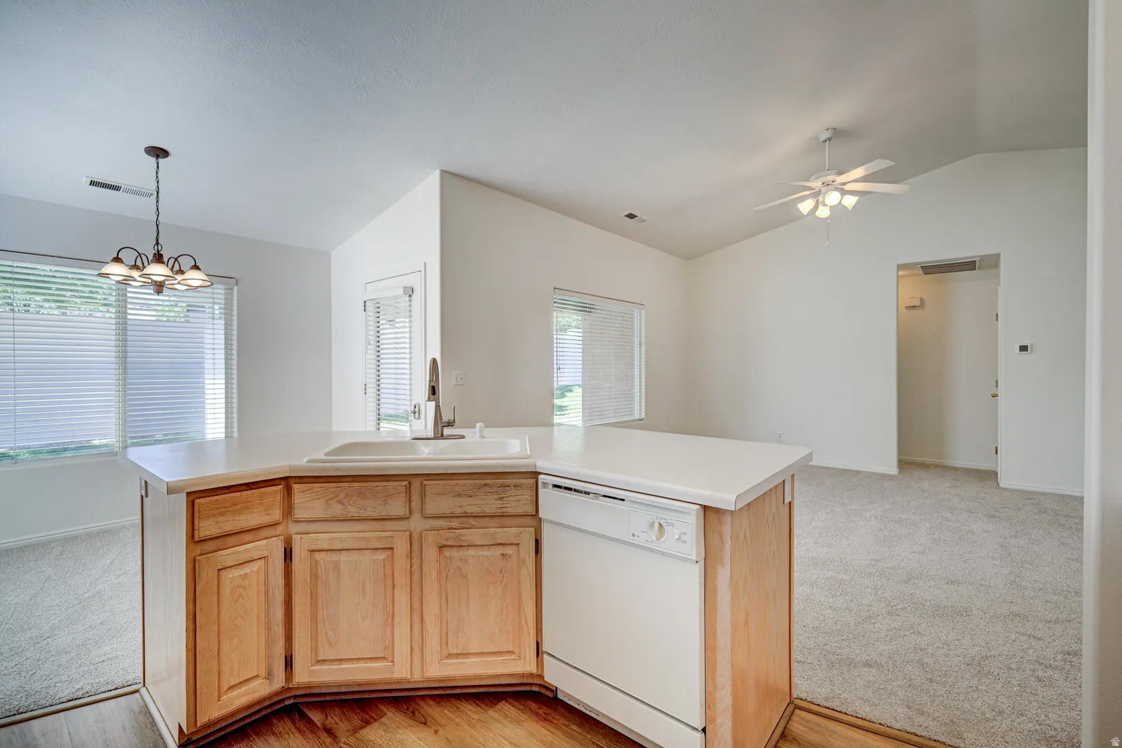 Kitchen peninsula with a built-in sink, integrated dishwasher, and light wood cabinetry
