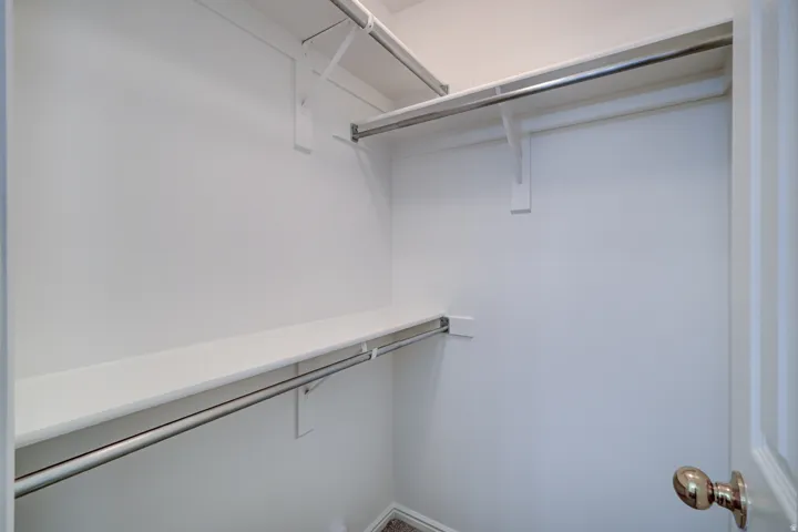 White-painted Primary Bedroom closet featuring multiple shelving units and chrome hanging rods