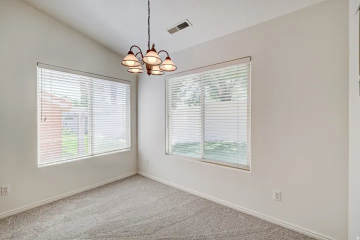 Room featuring a vaulted ceiling and a chandelier with five frosted glass shades