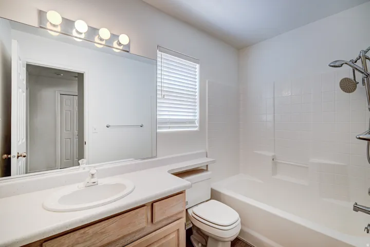 Main Hall Bathroom featuring a single vanity with a white countertop and wood-finish cabinetry, a large mirror, and a five-light fixture
