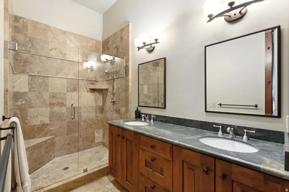 Spacious bathroom featuring a glass-enclosed shower with stone tile surround and built-in bench
