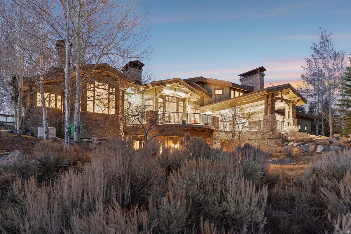 Expansive stone and wood-sided exterior featuring multiple balconies, prominent stone chimneys, large windows, and a multi-level design