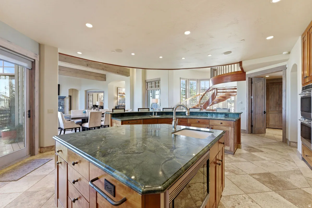 Gourmet kitchen with stone countertops, integrated sink, custom wood cabinetry, and stainless steel double ovens