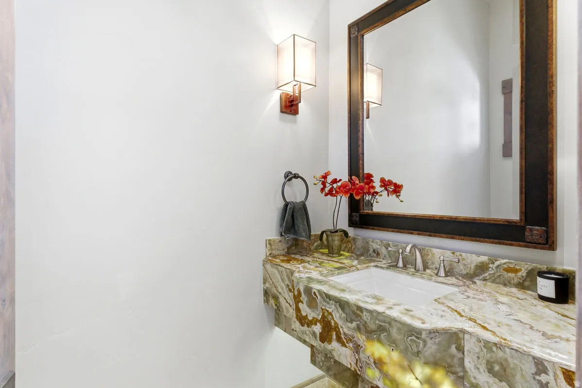 Vanity featuring a green and brown veined countertop with an undermount sink, brushed nickel faucet, and a large framed mirror