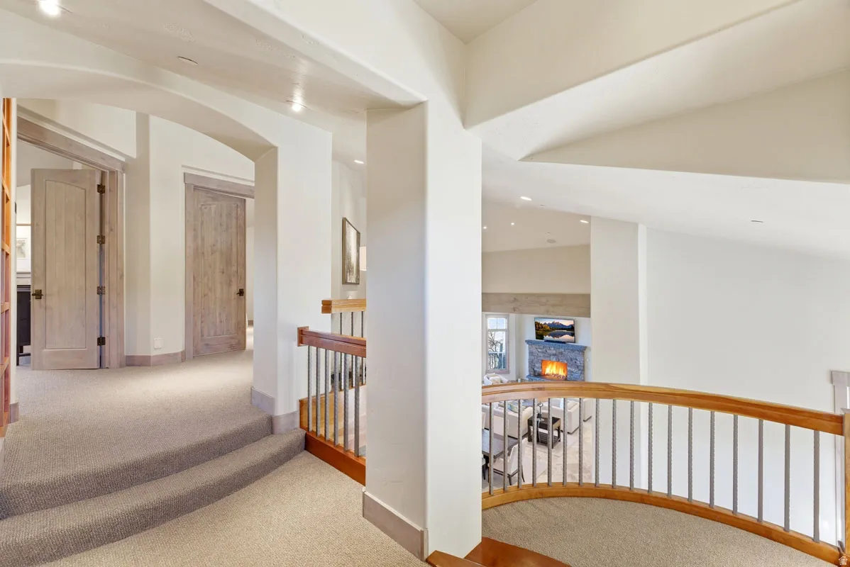 Upper-level hallway featuring light-toned carpeting and wood doors with black hardware
