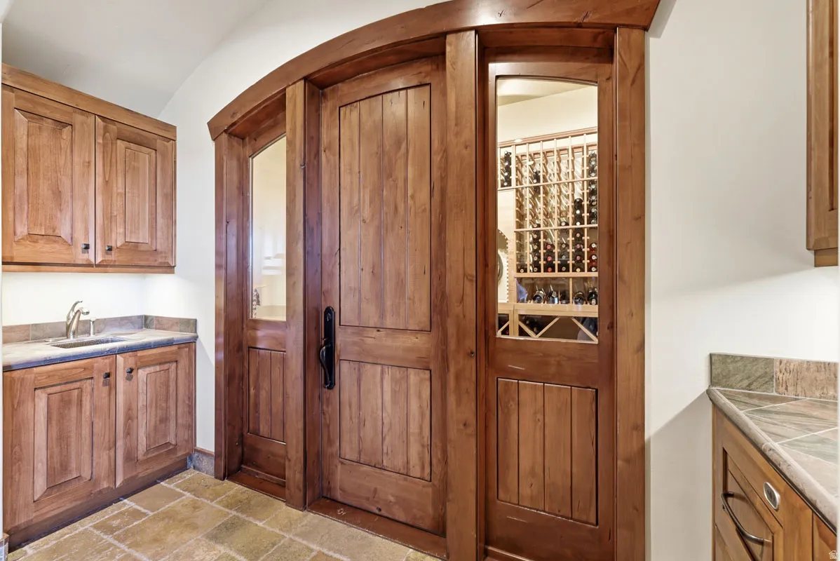Custom arched wood entry door with sidelights revealing a dedicated wine storage room