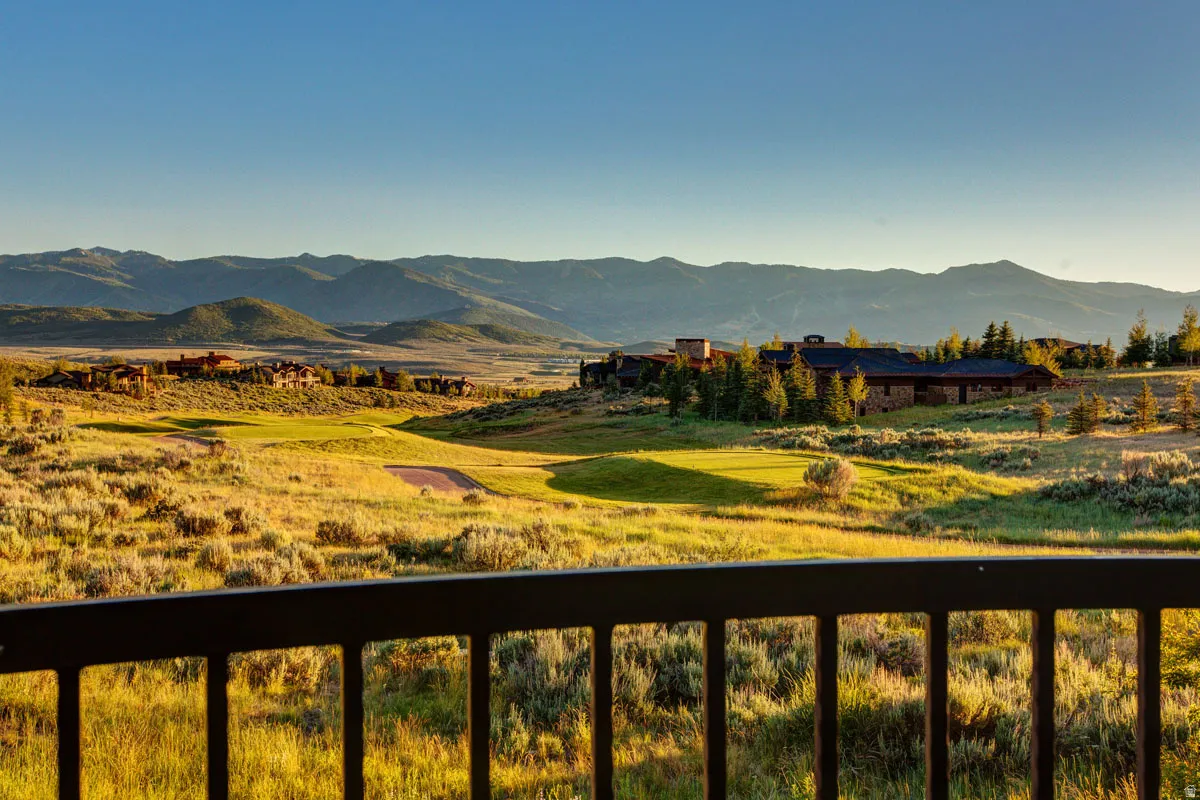Expansive landscape featuring distant mountains, a golf course, and a large structure with a dark roof and stone siding